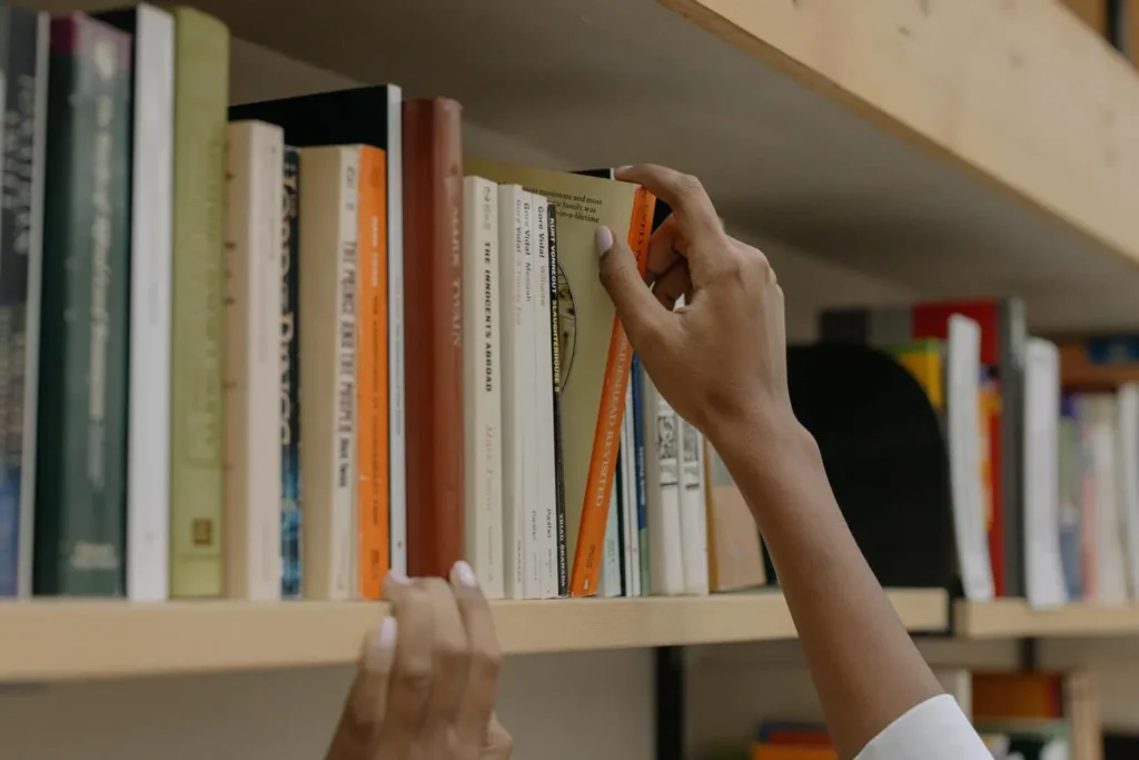 hand reaches for books on the bookshelf