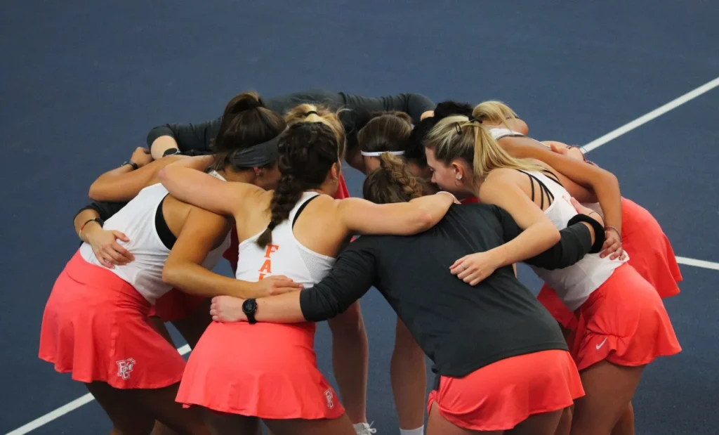 naispuolinen tennisjoukkue halaa toisiaan
